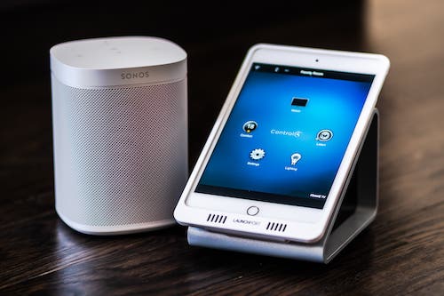 A smart phone sitting on a dock next to a Sonos speaker