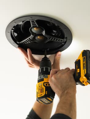 Close-up of someone drilling a mount onto a ceiling.