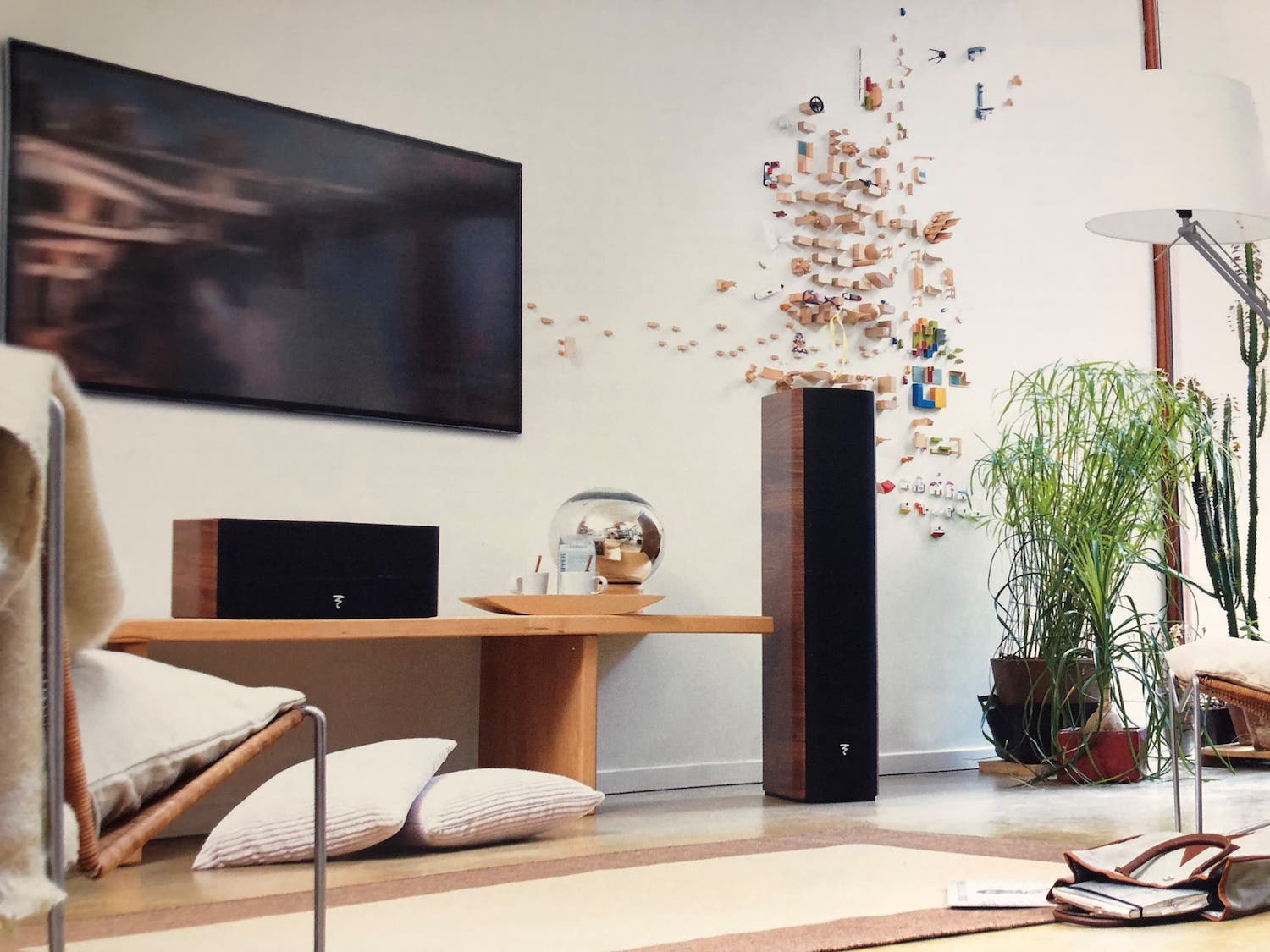 Living room with two large, wood-inlaid speakers and a TV mounted on the wall.